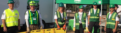 CERT volunteers in green vests and helmets staged at a community emergency response training site