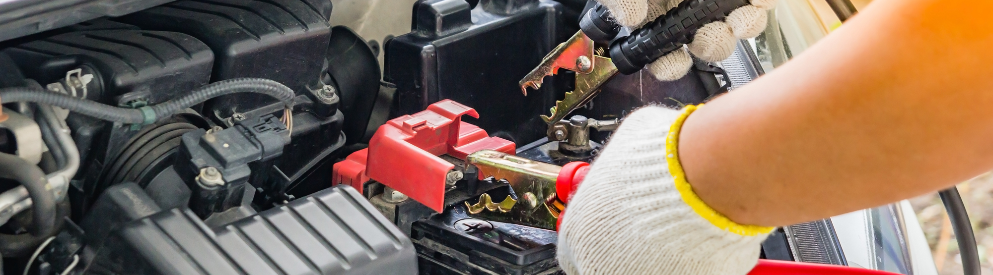 Hands jump starting a car battery. 