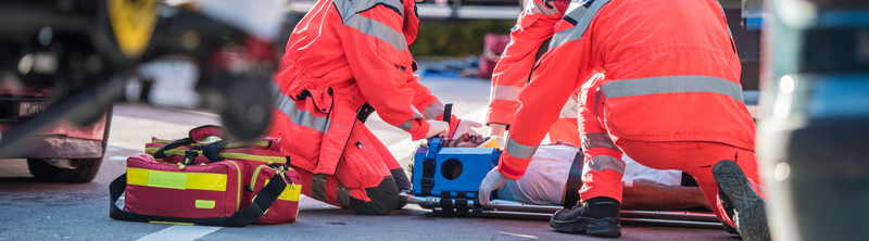 First responders treating a patient with a trauma bag on the left.
