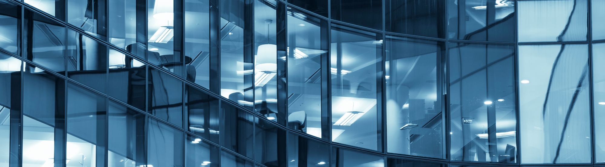 Modern glass office corridor with overhead lighting, representing Safety Kits Plus's government and corporate capabilities